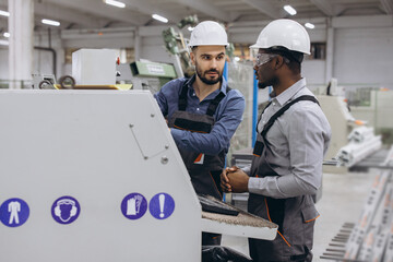 Engineers discussing while operating industrial machinery for PVC windows and doors production