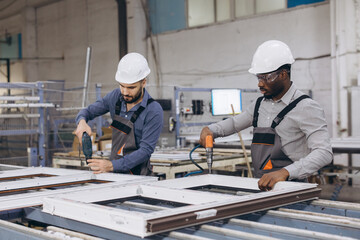 Factory workers assembling PVC window frames on production line