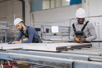 Fototapeta premium Factory workers assembling aluminum and pvc window frames