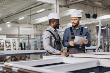 Factory workers discussing aluminum window frame production