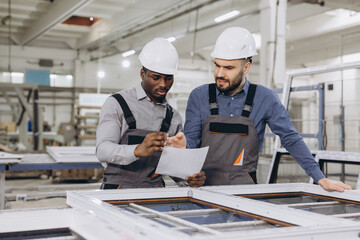 Engineers examining aluminum and pvc window frame in factory