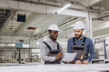 Engineers discussing aluminum window frames production in factory