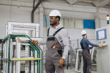 Factory worker moving aluminum window frames on production line