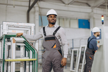 Factory worker posing near aluminum window frames inside workshop