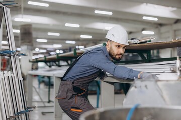 Factory worker controlling aluminum and PVC windows and doors production