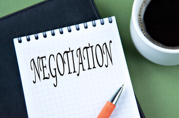 NEGOTIATION - word in notebook on green background with cup of coffee