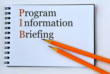 PROGRAM INFORMATION BRIEFING - words in notebook on white background with pencils