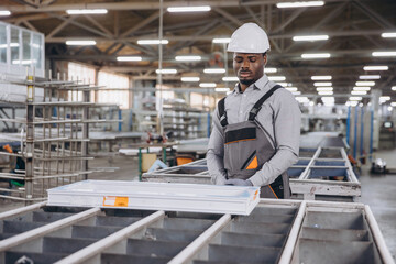 Factory worker inspecting aluminum window frame on production line