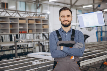 Factory worker posing with crossed arms in a PVC windows and doors production line