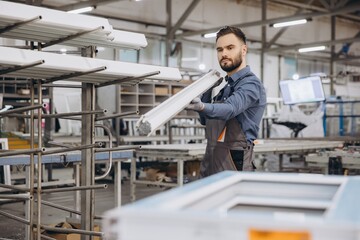 Factory worker carrying pvc window frame in production line