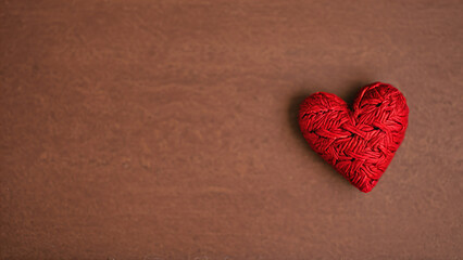 Obraz premium knitted red heart on a brown surface