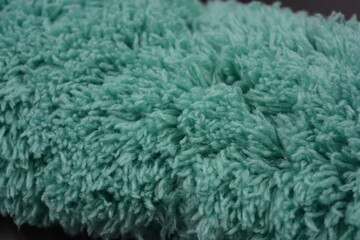 Beautiful green soft fluffy, nylon, synthetic fabric arranged on a black plastic background.