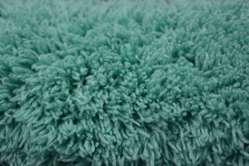 Beautiful green soft fluffy, nylon, synthetic fabric arranged on a black plastic background.