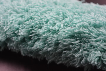 Beautiful green soft fluffy, nylon, synthetic fabric arranged on a black plastic background.