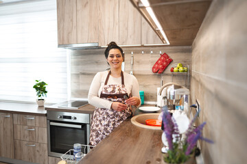 Obraz premium Happy woman wearing apron in the kitchen