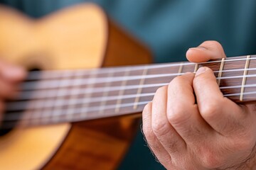 Fototapeta premium A close-up of a person's hand playing a wooden guitar, showcasing intricate finger placement on the strings.