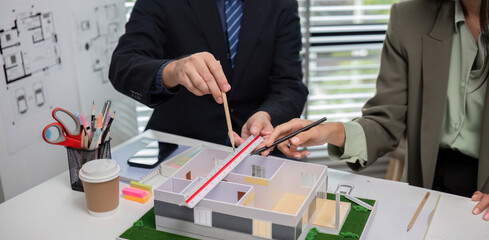 Architectural Team Collaborating on Modern House Design with Scale Model and Blueprints in Office Setting
