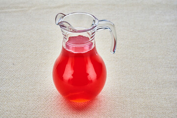 A glass pitcher of red liquid sits on a table