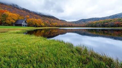 Fototapeta premium Serene autumn lake with cabin reflection.
