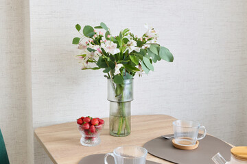 A Cozy Dining Setup Featuring Fresh Flowers and Ripe Strawberries for a Delightful Experience