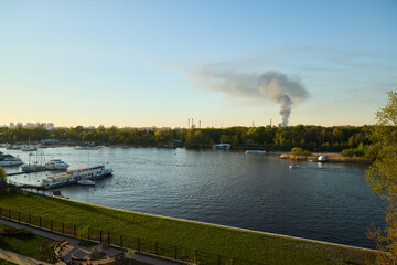 Naklejka premium A picturesque river view featuring smoke in the background during the beautiful dusk