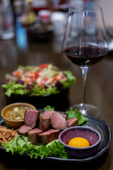 Grilled beef tongue served on plate with pickled egg yolk and sauce