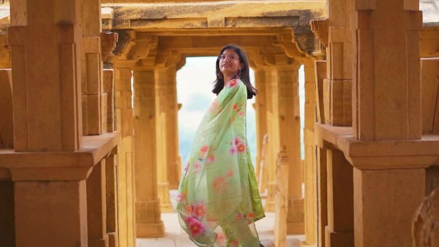 Indian girl exploring architecture of Bada Bagh cenotaphs in Jaisalmer, Rajasthan, India. Tourist on vacation. Travel, history, ancient architecture concept. Indian girl wearing salwar suit.