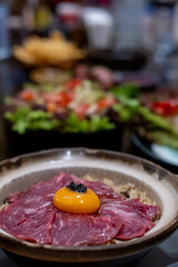Beef fat fried rice in a bowl, with sliced meat and egg yolk on top