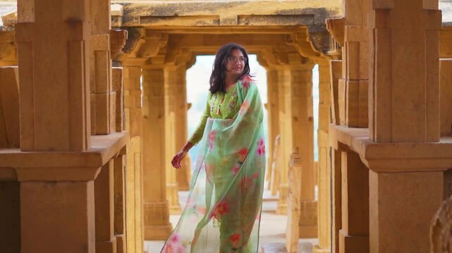 Indian girl exploring architecture of Bada Bagh cenotaphs in Jaisalmer, Rajasthan, India. Tourist on vacation. Travel, history, ancient architecture concept. Indian girl wearing salwar suit.
