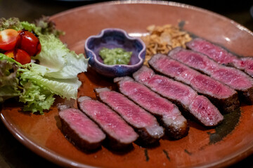 Medium rare sliced rib eye meat served on plate with vegetable