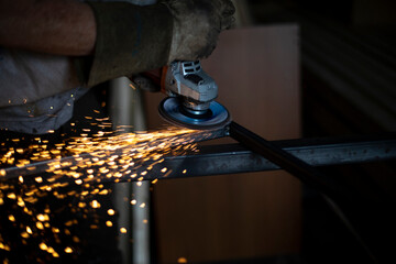 Sparks from grinding steel. Man works in garage. Metal treatment.