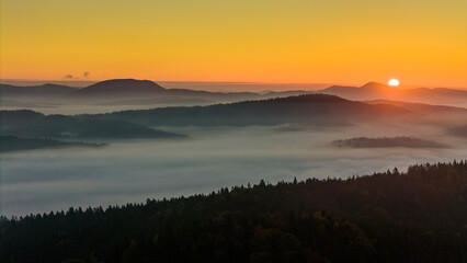 Aerial drone view of sunrise above clouds in mountains