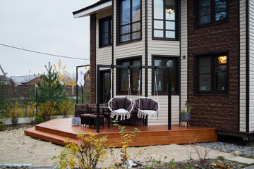 A stunning modern house exterior featuring a cozy deck with inviting swing chairs for relaxation