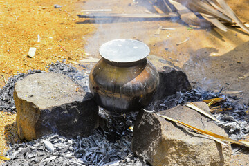 A traditional Indian cooking scene, likely during a festival or rural household ritual....