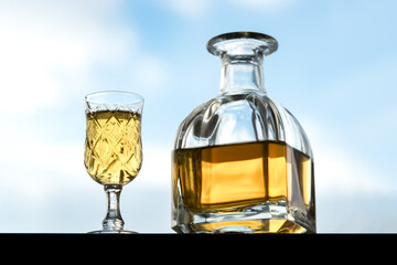 Close-up Of Drink In Glass. Decanter full of Whiskey with a glass on the sky background.