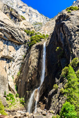 A waterfall is seen in the distance with a group of people standing near it