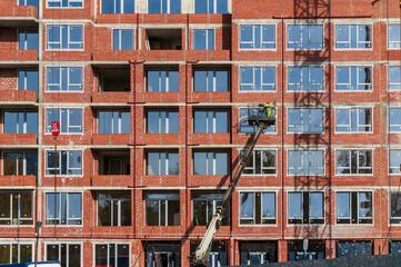 Installation of double-glazed windows in a new multi-story residential brick building using a facade lift