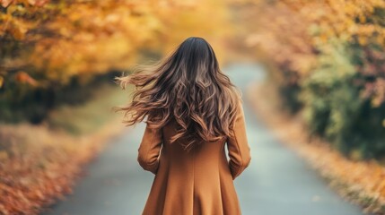 Obraz premium Woman in Autumn Coat Walking Down Scenic Path Surrounded by Trees