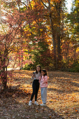 Fototapeta premium Two girls are looking at their cell phones in a forest