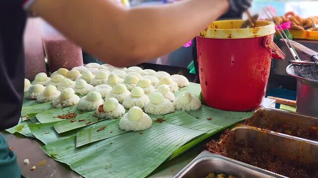 Stall vendor preparing the delicious Nasi Lemak on a banana leaf. 4K video shot of Malaysia Street food.