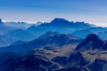 Aerial view of the mountain silhouettes on the horizon. Misty and foggy sky with Dolomites mountain range on the horizon. Blue mist in the mountains