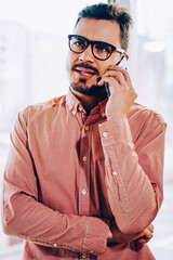 Male businessman making dissatisfied face while talking with service operator on mobile phone,...