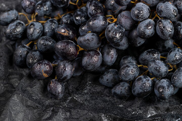 fresh grapes are lying on black paper