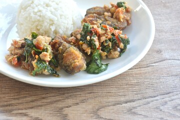 slice boiled black preserved egg dressing spicy fried chop pork meat and basil leaf on plain rice in plate