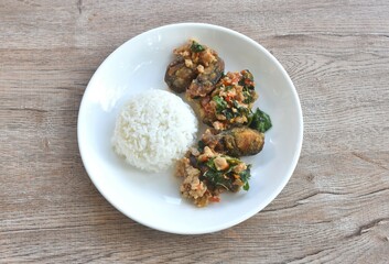 slice boiled black preserved egg dressing spicy fried chop pork meat and basil leaf on plain rice in plate