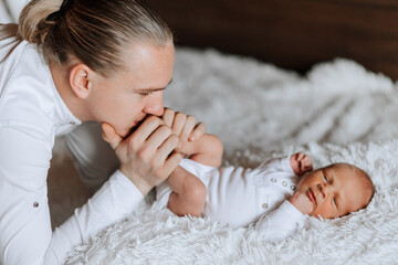 A man is holding a baby's foot and kissing it. The baby is sleeping and the man is looking at it