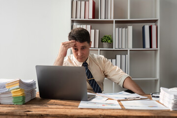 Young Businessman Focused on Work at Desk with Laptop and Documents in Modern Office Environment