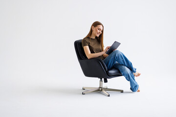 Beautiful woman sitting on a chair with a tablet isolated over a white background