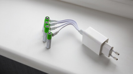 Four rechargeable batteries with plugged in USB plug charging wires in power adapter