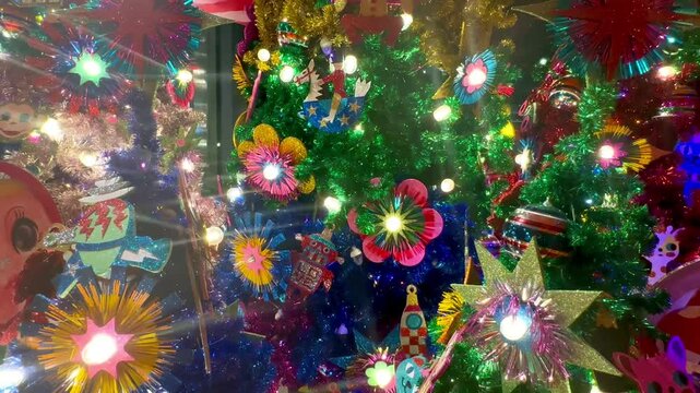 This vibrant Christmas tree features colorful artificial flowers and sparkling stars, beautifully adorned with twinkling lights and flashing bulbs, creating a festive atmosphere perfect for holiday ce